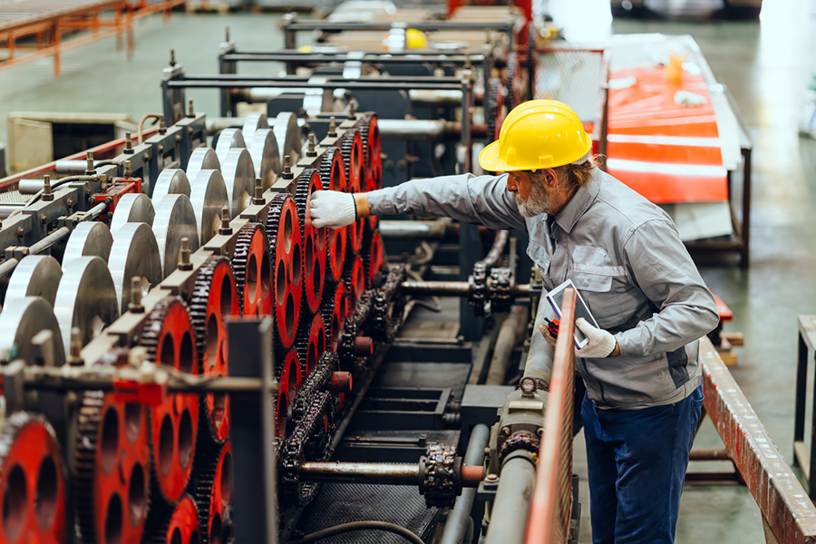 Worker inspecting machinery in factory